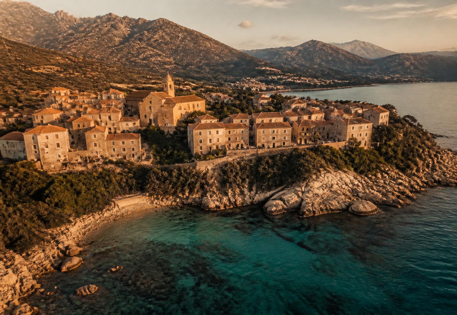 Village corse au bord d'une crique méditerranéenne au coucher du soleil